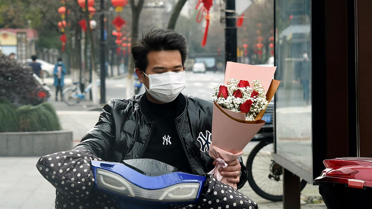 Photo of a man wearing a face mask carrying a bouquet