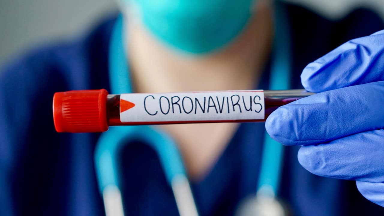 Photo of a physician holding a vial of blood marked coronavirus