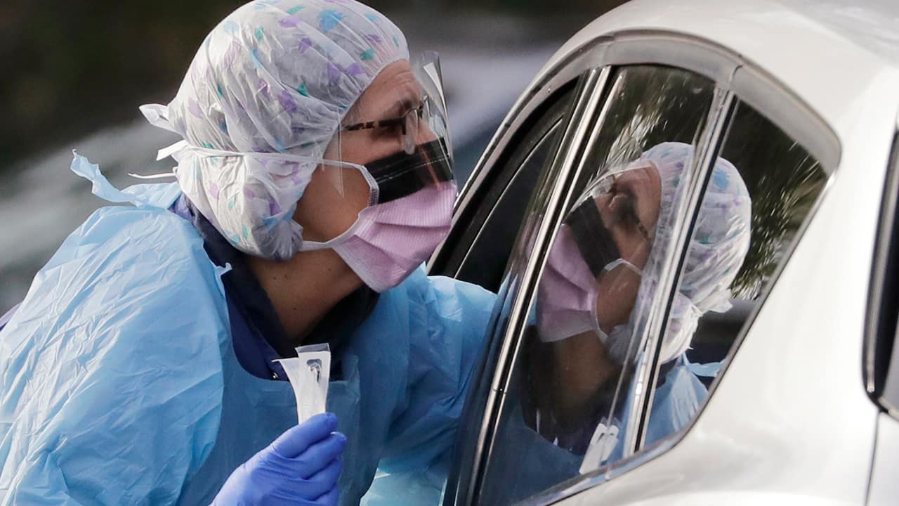 Photo of a nurse reaching into a car