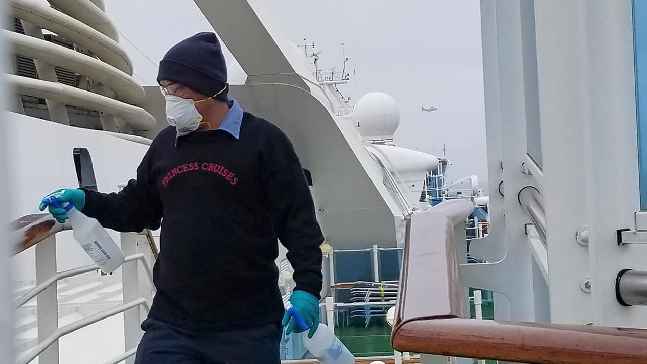 Photo of a cruise ship worker cleaning a railing