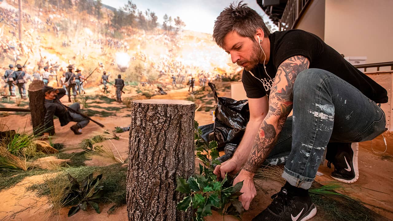 Photo of a worker putting final touches on diorama