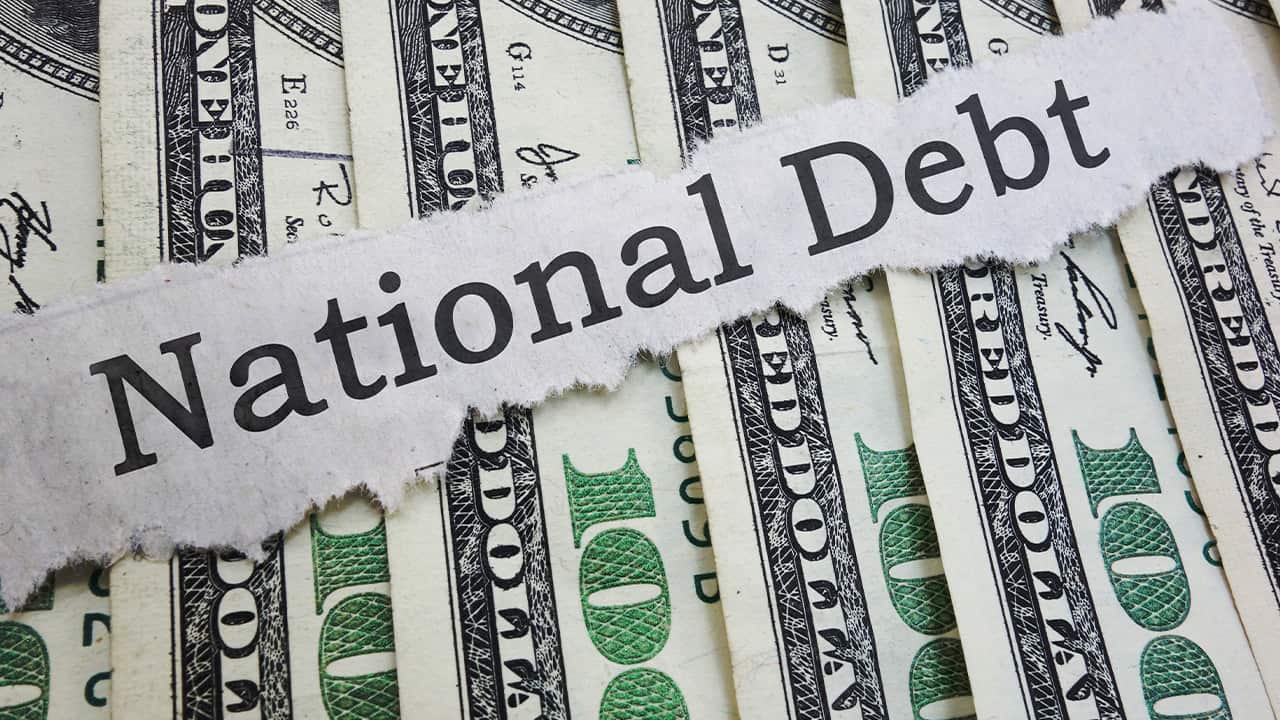 Photo of money and "national debt" on a ripped piece of paper