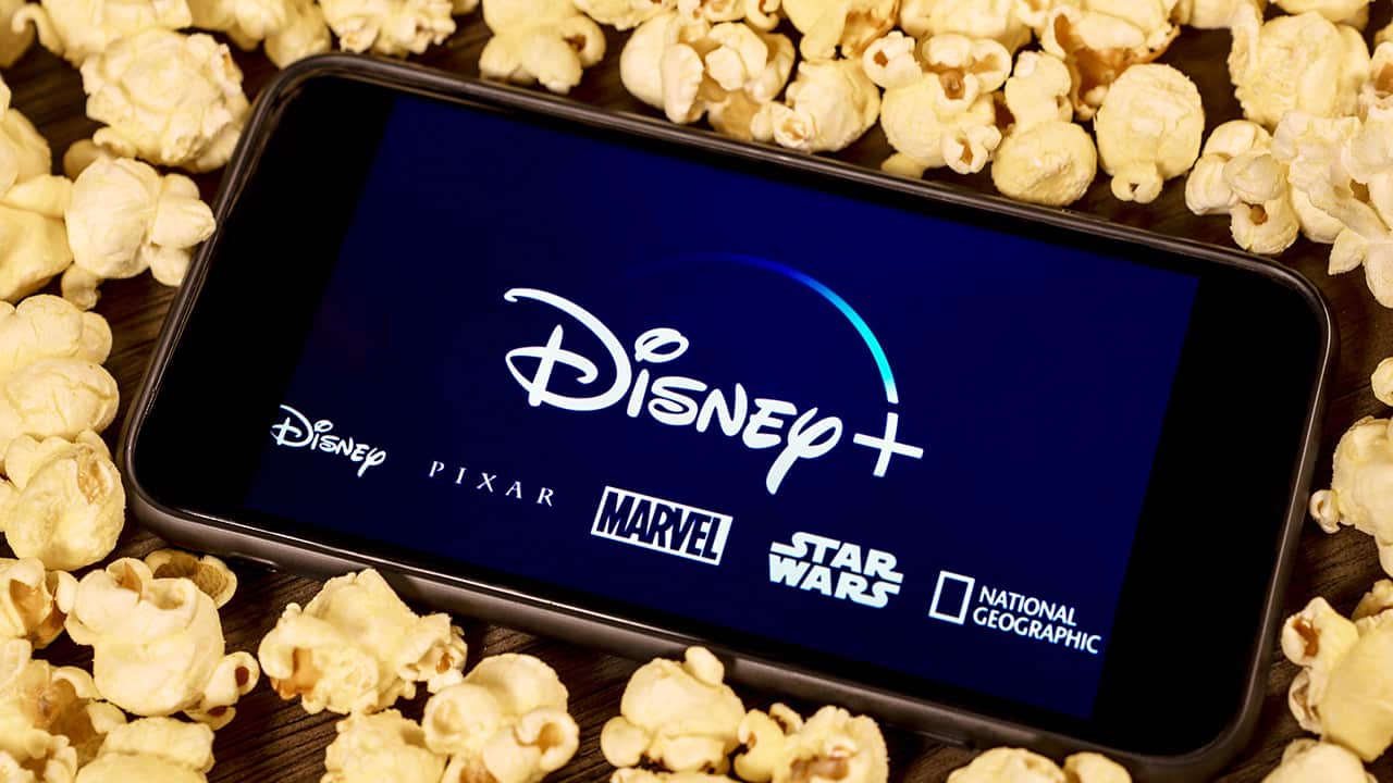 Photo of an iPhone with Disney Plus on the screen surrounded by popcorn