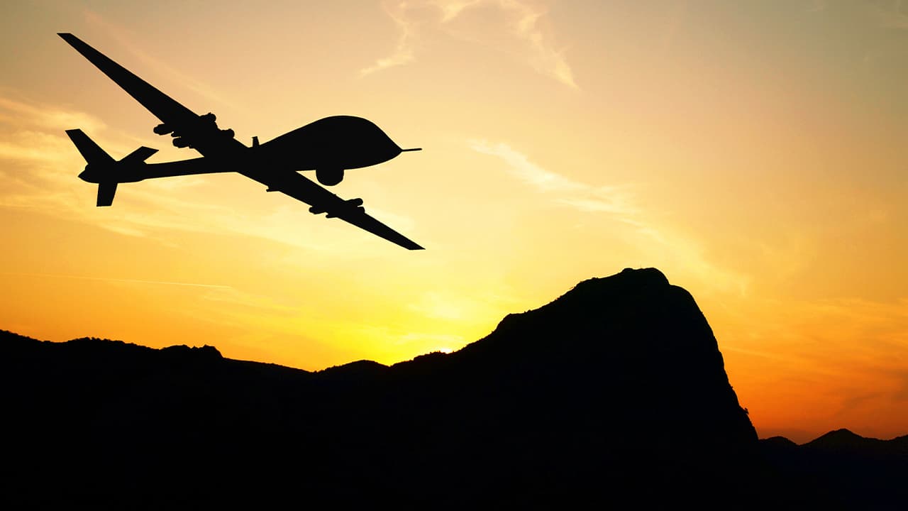 Photo of a military drone silhouette against a sunset