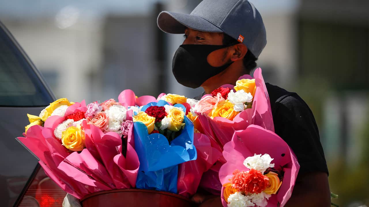 Photo of a man selling flowers and wearing a face mask 