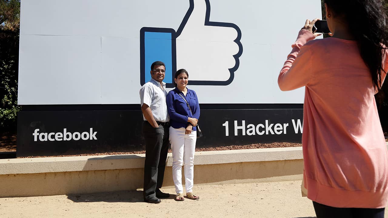 Photo of visitors taking pictures in front of the Facebook logo