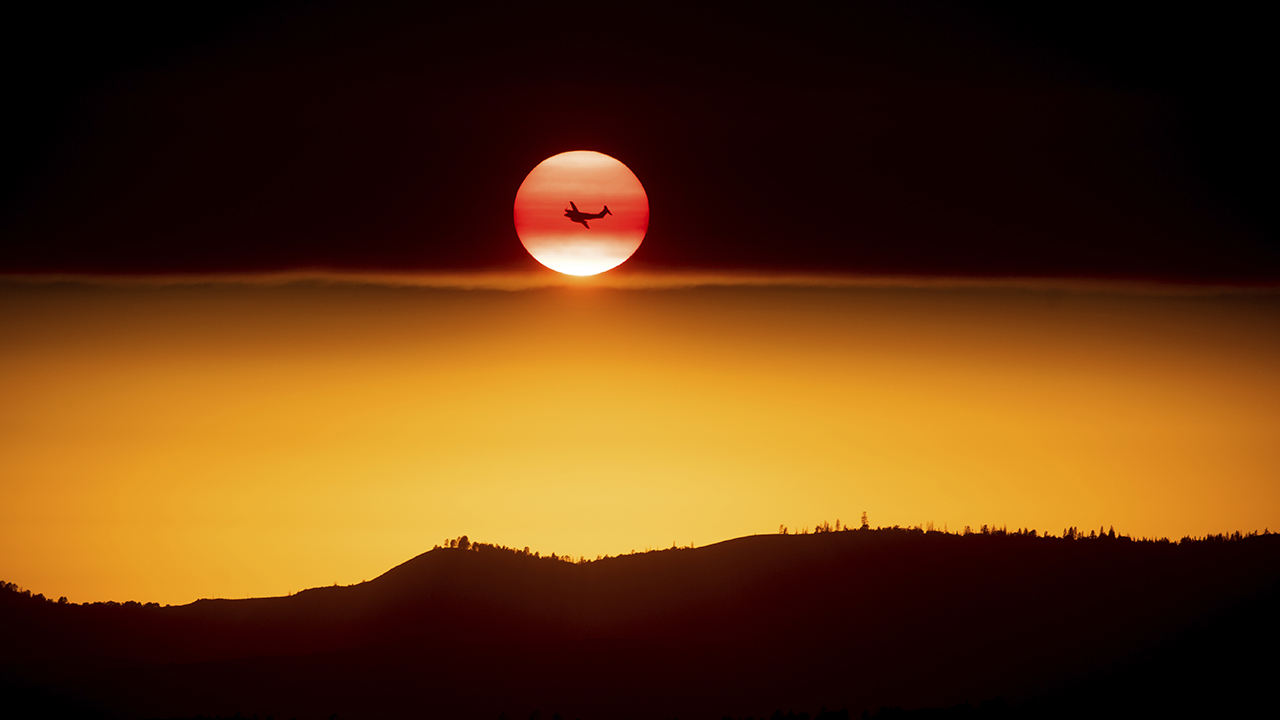Photo of plane fighting the Ferguson Fire passing a setting sun