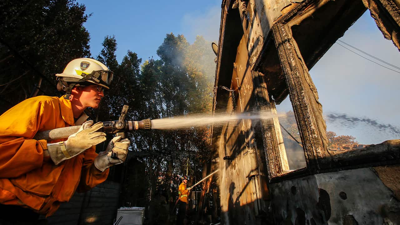 Photo of a firefighter spraying a hose 