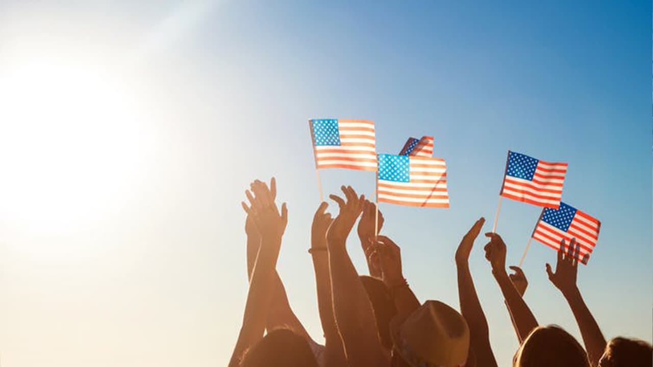 Photo of a blue sky and people holding American flags