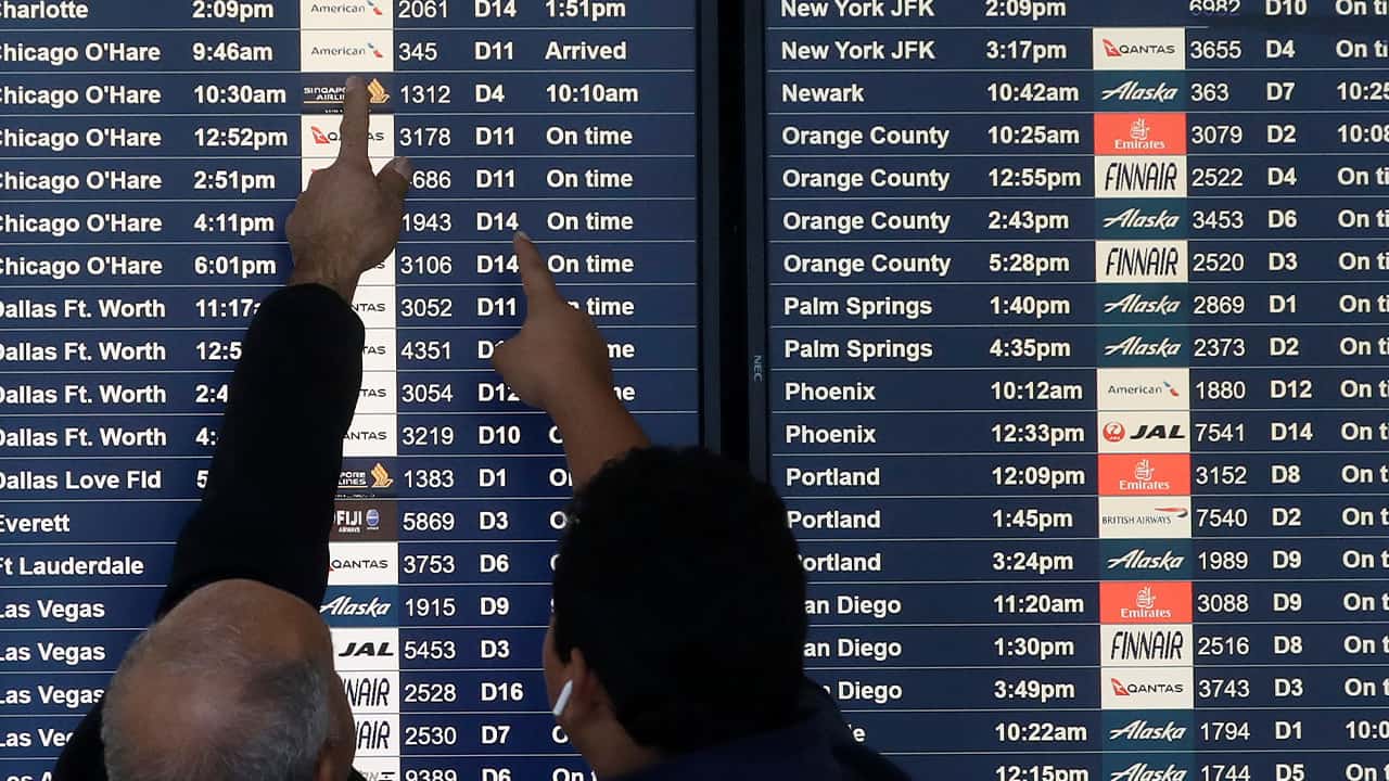 Photo of men pointing at flight arrival times 