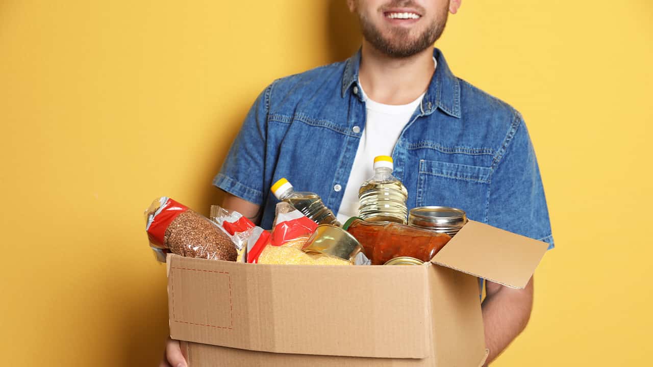 Picture of a young man carrying a box of donated groceries