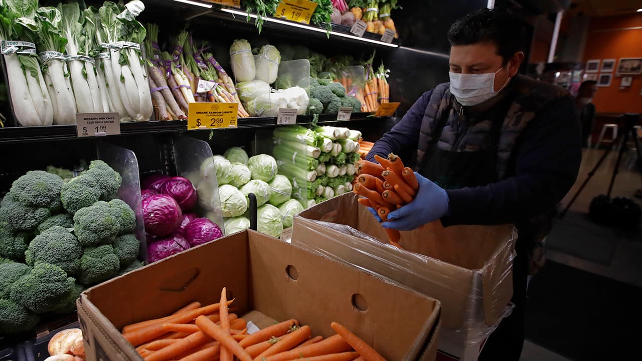 Photo of a worker stocking produce