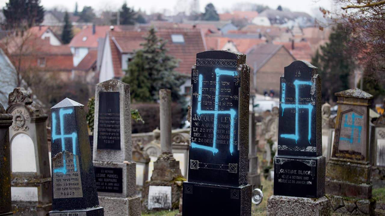 Photo of gravestones vandalized with swastikas