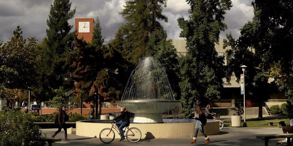 Students walk and cycle past the centerpiece fountain at Fresno State