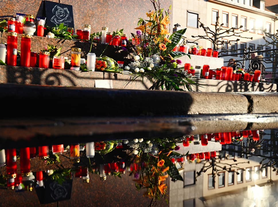 Photo of flowers and candles set around a monument for the brothers Grimm