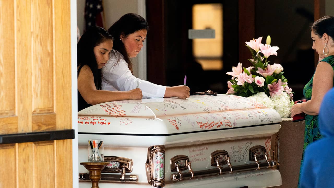 Photo of mourners writing on Keyla Salazar's casket during her funeral