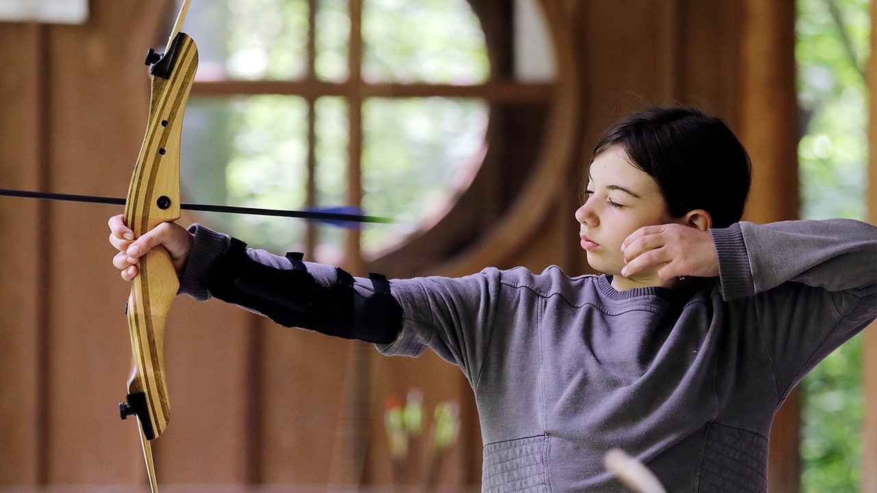Photo of a girl scout releasing an arrow during archery session