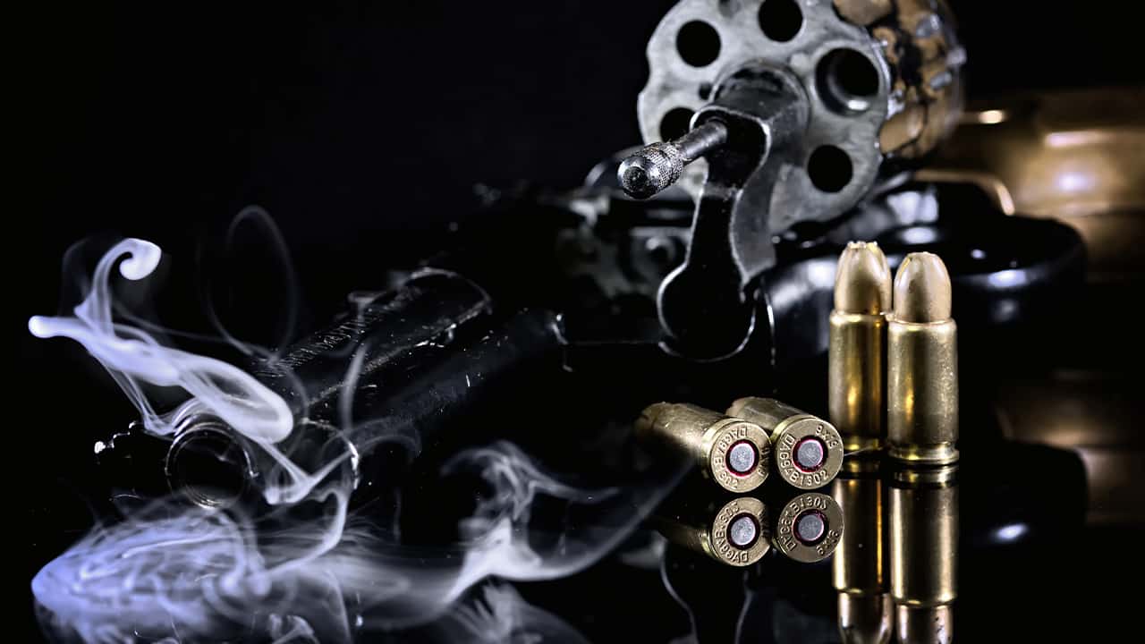 Photo of a Colt revolver, cartridges and smoke