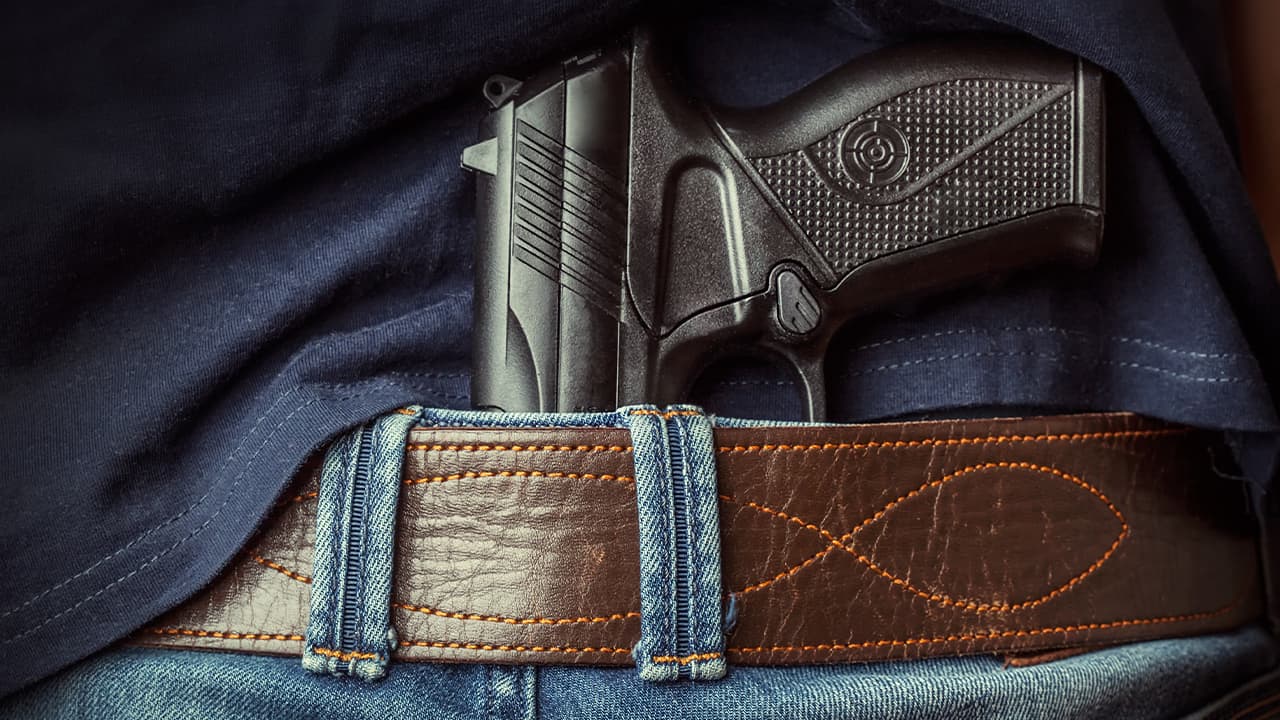 Photo of a man with a gun tucked under his belt in back