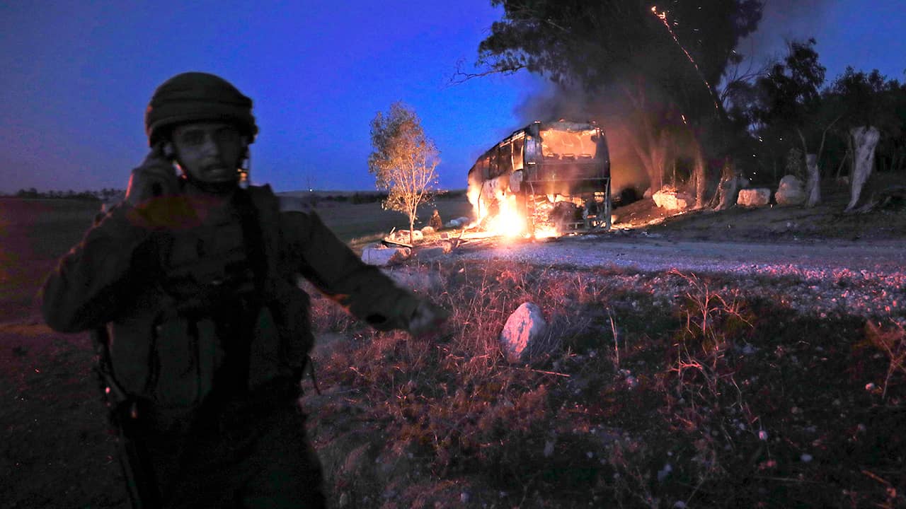 Photo of an Israeli soldier standing next to a burning bus