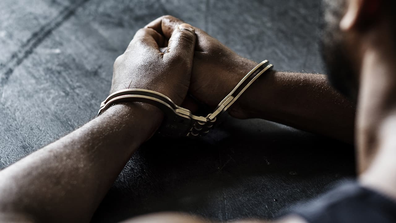 Photo of a man in handcuffs sitting at a table
