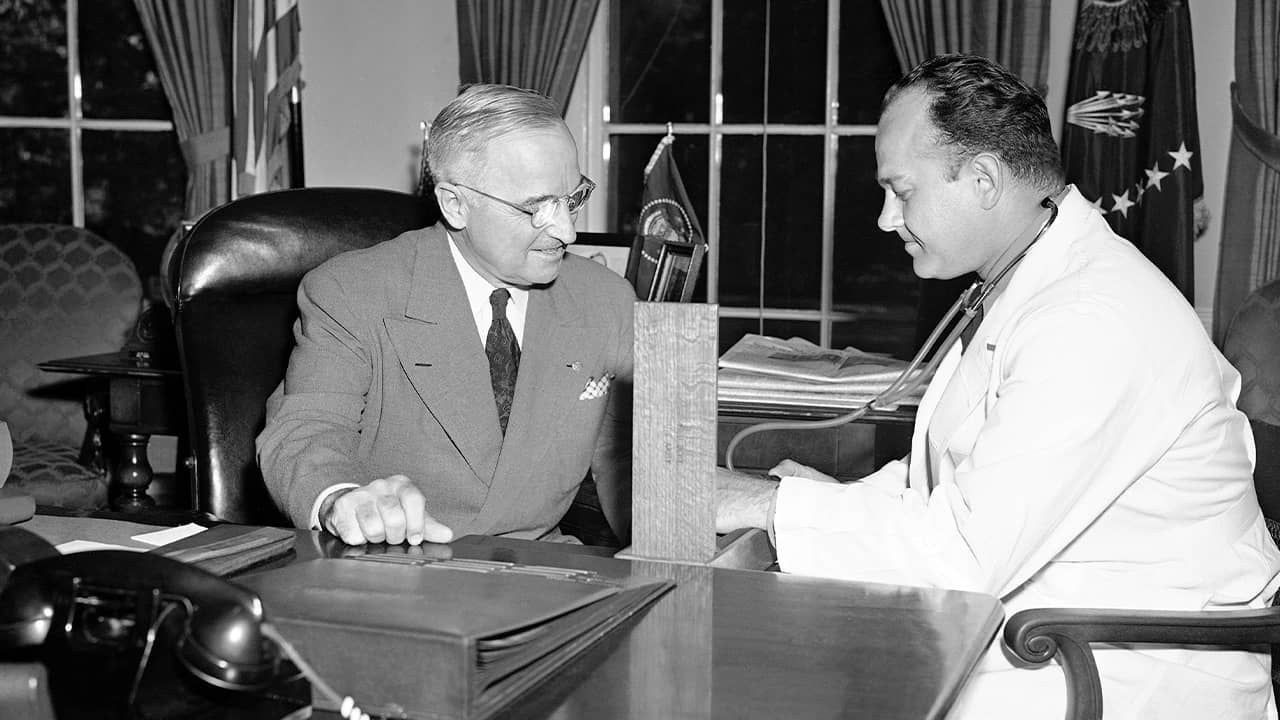 Photo of Brigadier Gen. Wallace Harry Graham, right, personal physician of President Harry S. Truman checking his blood pressure