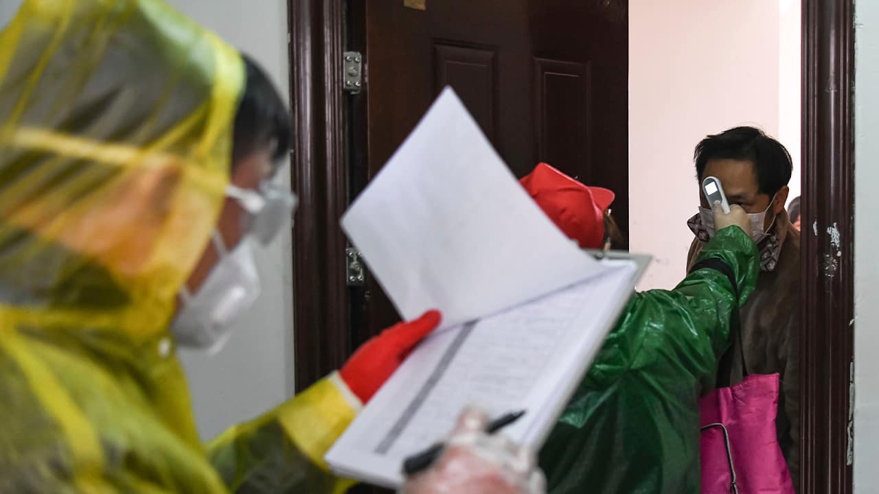 Photo of workers checking the temperature of residents during a health screening 