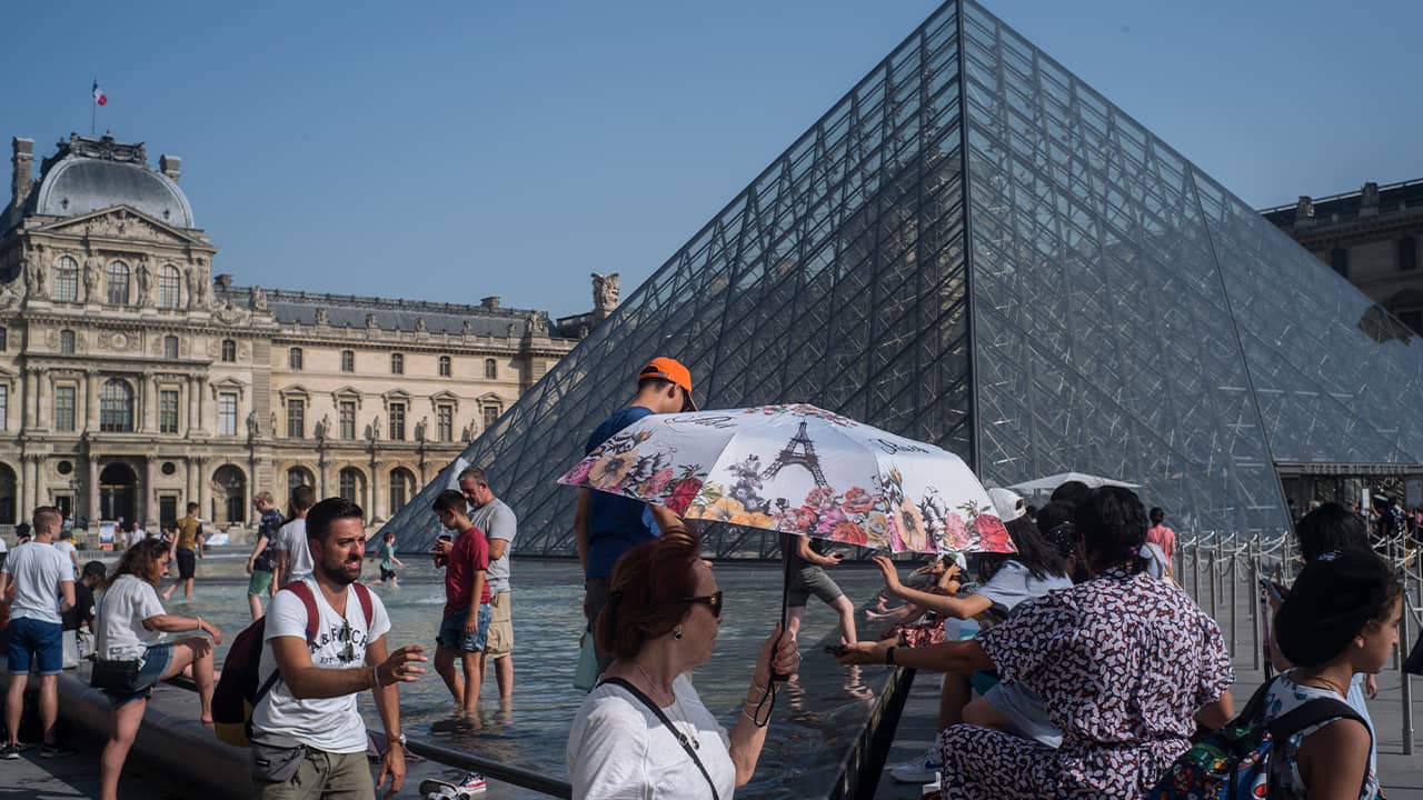 Photo of people cooling next tot he fountain at Louvre Museum in Paris