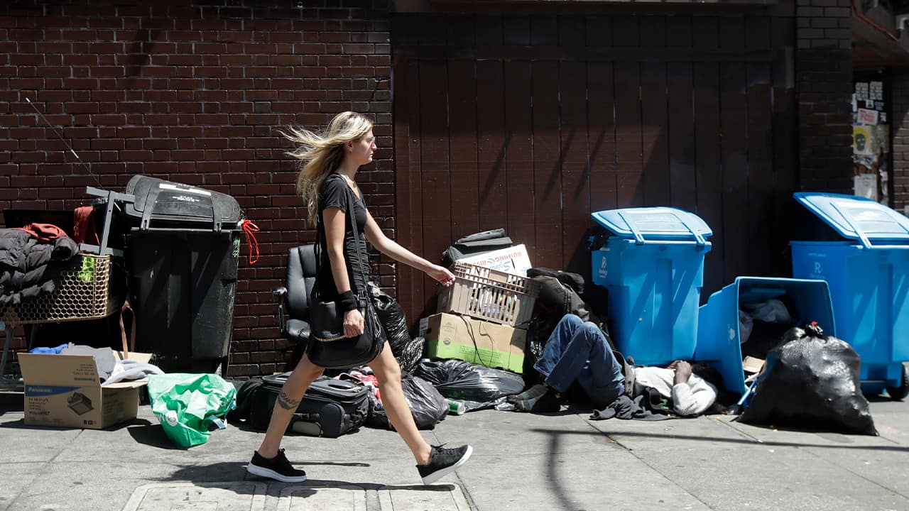 Photo of a middle-class woman walking past a homeless man and garbage in San Francisco