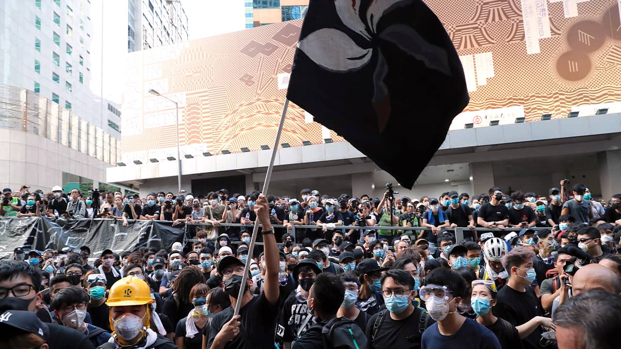 Photo of a protestor waving a black version of the Hong Kong flag