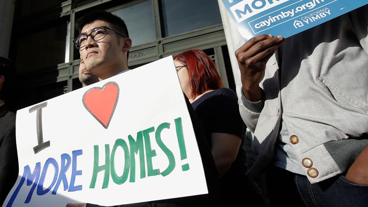 Photo of men holding up signs at a rally outside of City Hall in Oakland, Calif.