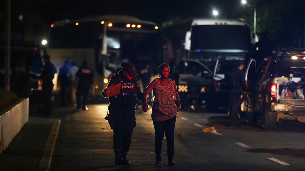 Photo of a migrant being escorted by a state police officer 