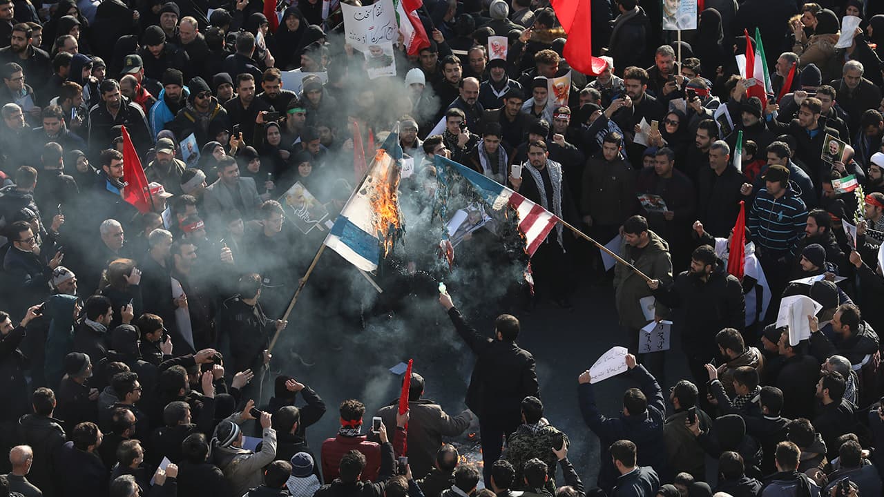 Photo of mourners burning mock flags of the U.S. and Israel during a funeral ceremony for Iranian Gen. Qassem Soleimani