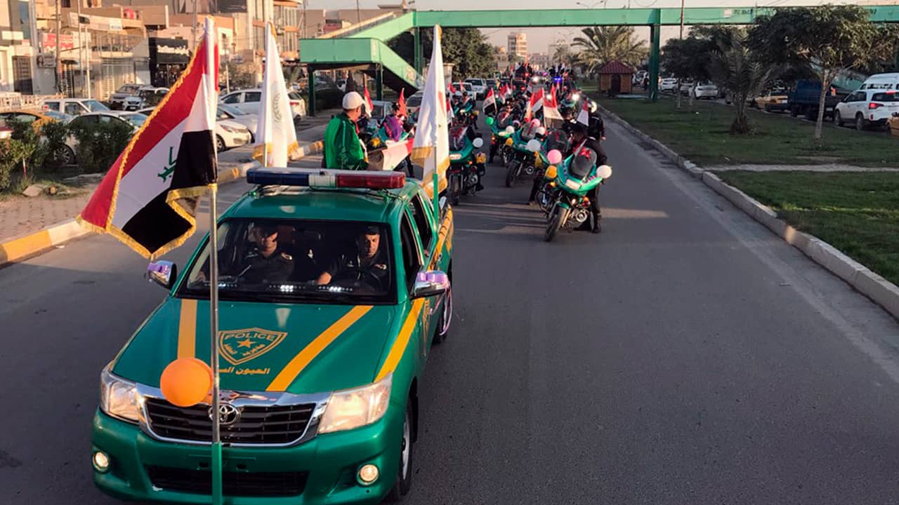 Photo of Iraqi security forces raising national flags in a parade