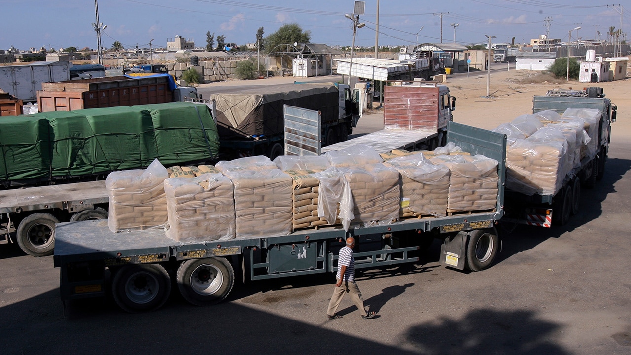 Photo of Palestinian worker next to cargo trucks