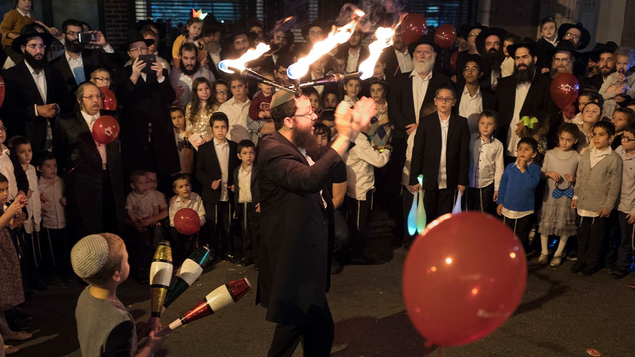 Photo of a performer wearing lighted sticks on his head while entertaining a crowd during the Jewish holiday of Sukkot