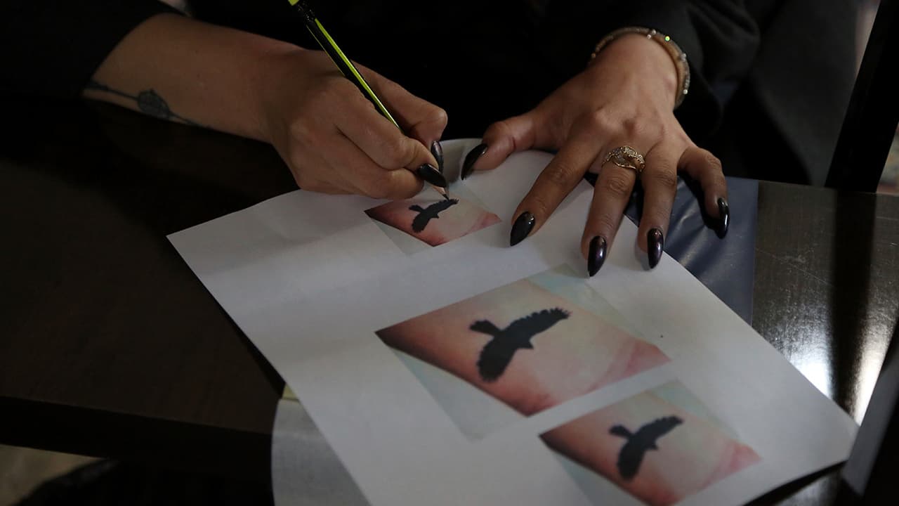 Photo of Suraya Shaheedi, 26, taking a copy of a tattoo 