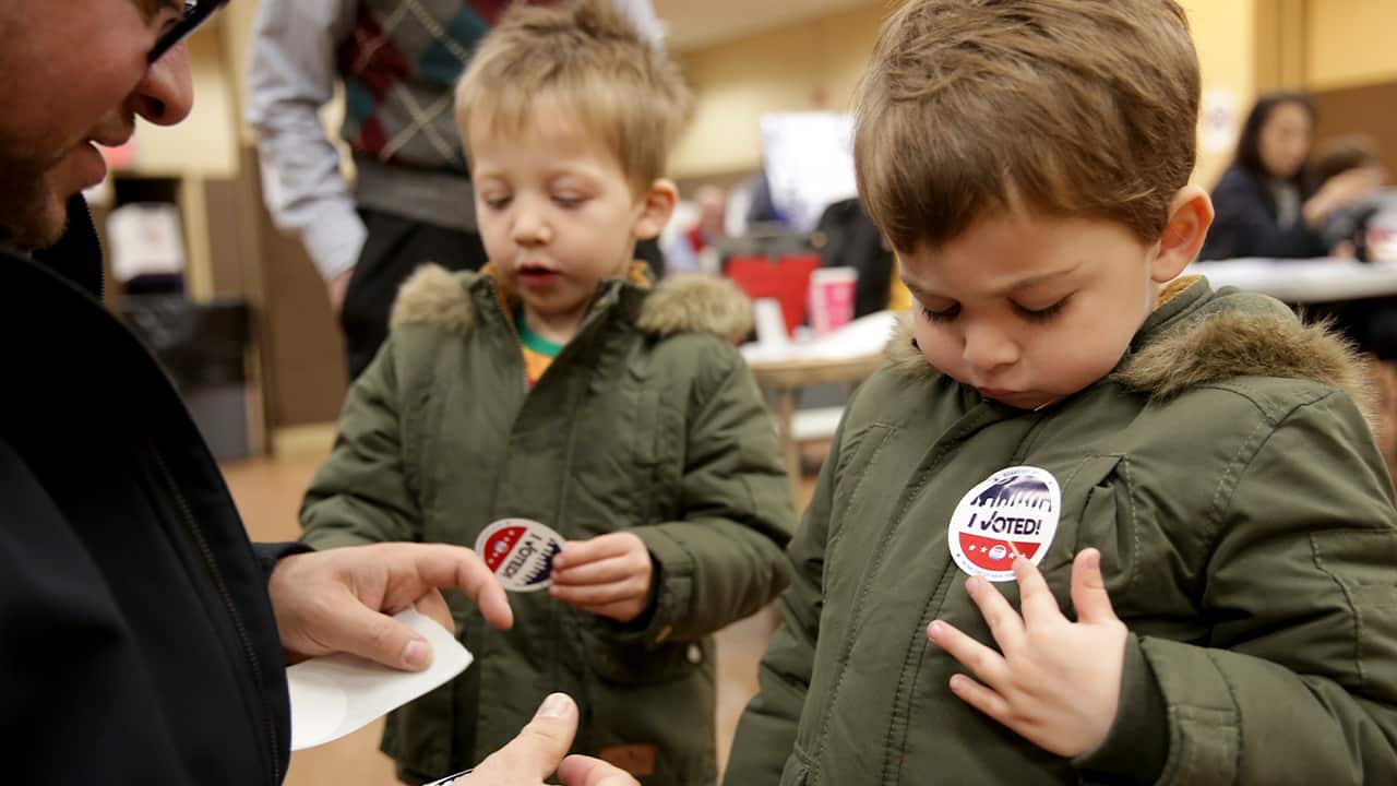 Photo of kids putting on an "I Voted" sticker