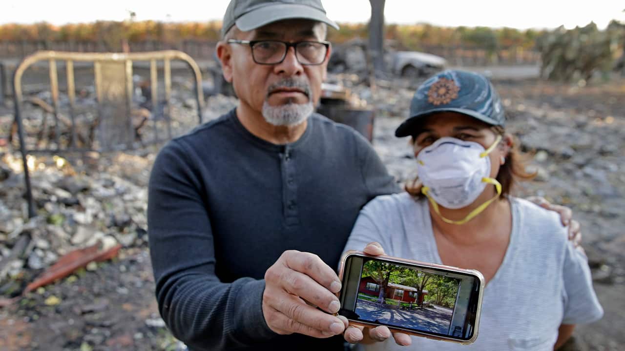 Photo of Justo and Bernadette Laos showing a photo of their home before it burned down