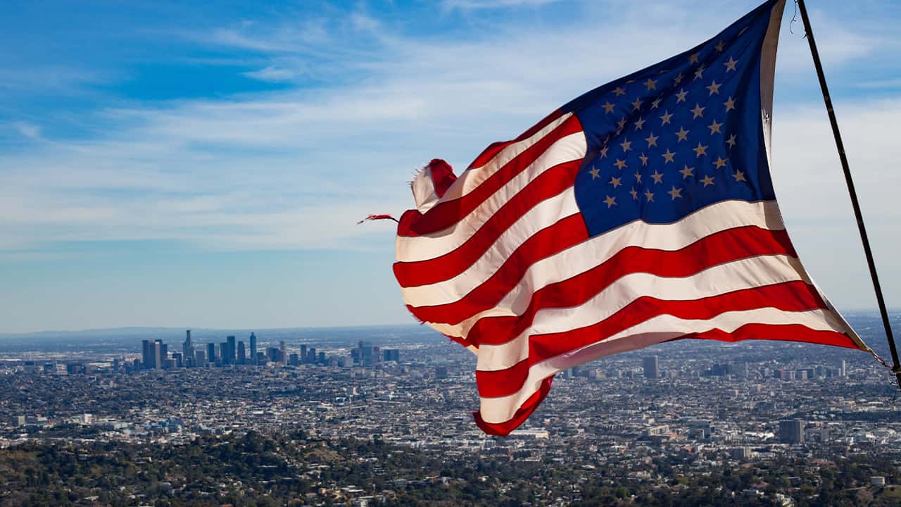 Photo of a flag waving with Los Angeles skyline in the background