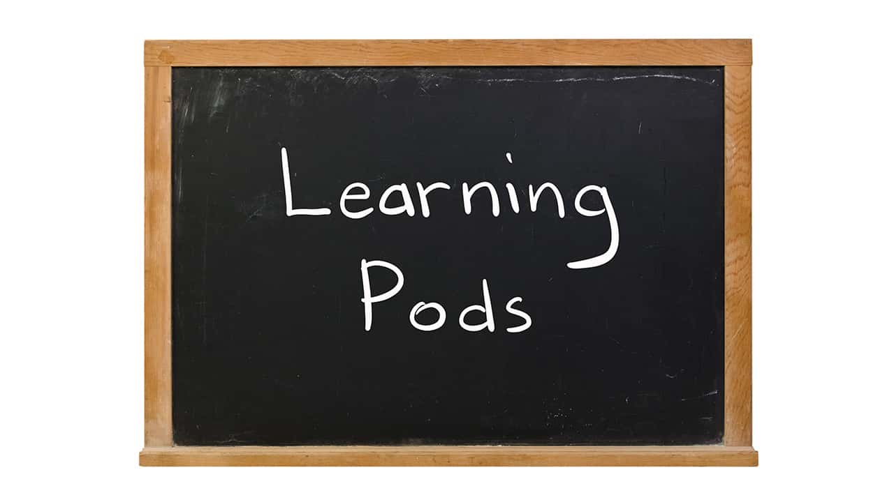 The words "Learning Pods" written in white chalk on a blackboard