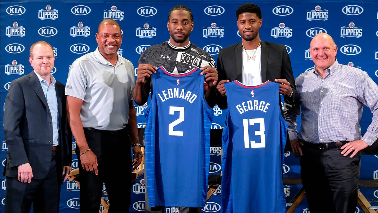 Photo of Kawhi Leonard, center, and Paul George, second right, holding their new team jerseys, with Los Angeles Clippers President of Basketball Operations Lawrence Frank, left, head coach Doc Rivers, second left, and team chairman Steve Ballmer