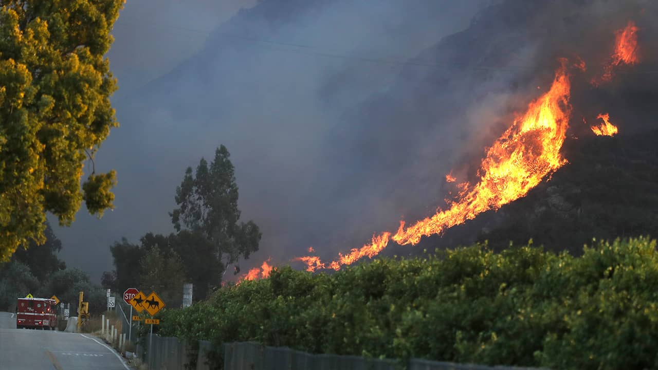 Photo of a wildfire coming down a hilltop in Malibu, CA