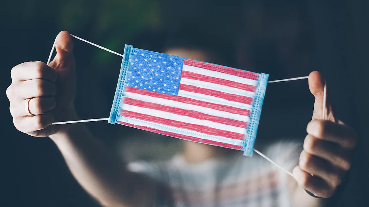 Photo of a man showing off a medical mask with an American flag on it