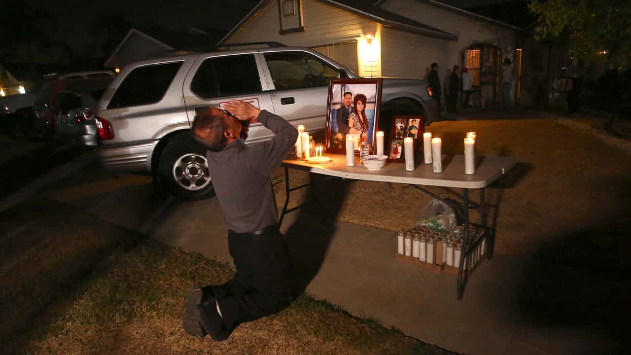Photo of Neej Xiong, uncle of shooting victim Kou Xiong, praying in front of a memorial during a candle light vigil in Fresno