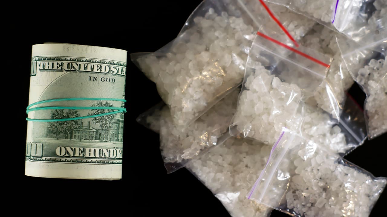 Photo of a roll of money and dime bags of meth