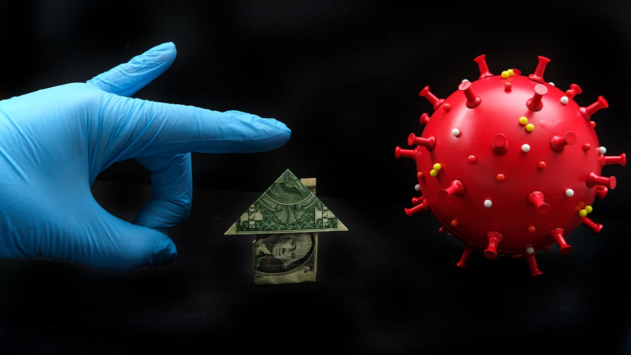 Image of a gloved hand, a dollar bill folded into the shape of a house, and coronavirus symbolizing challenges of paying rents and mortgages during the pandemic