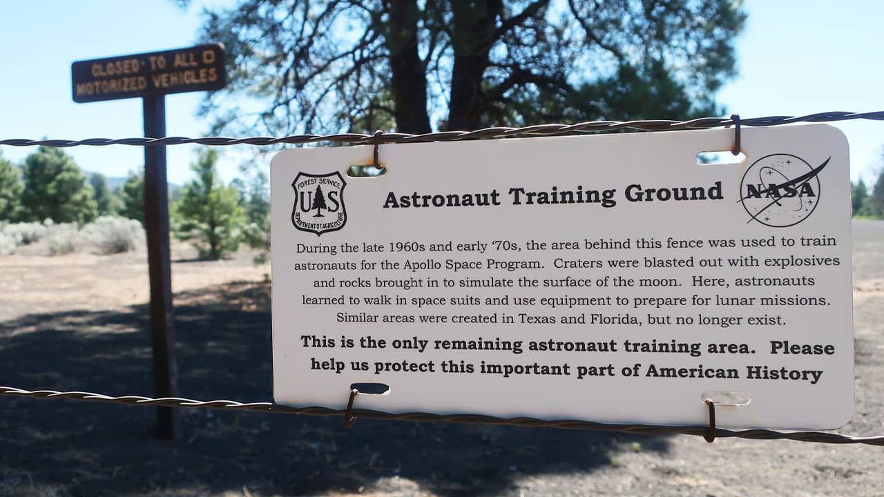 Photo of a sign and fenced off field of craters in a volcanic cinder field 