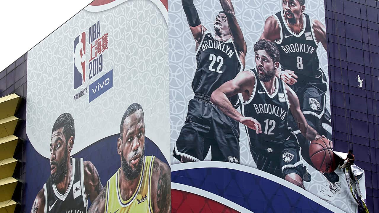 Photo of a worker taking down a billboard advertising an NBA preseason basketball game