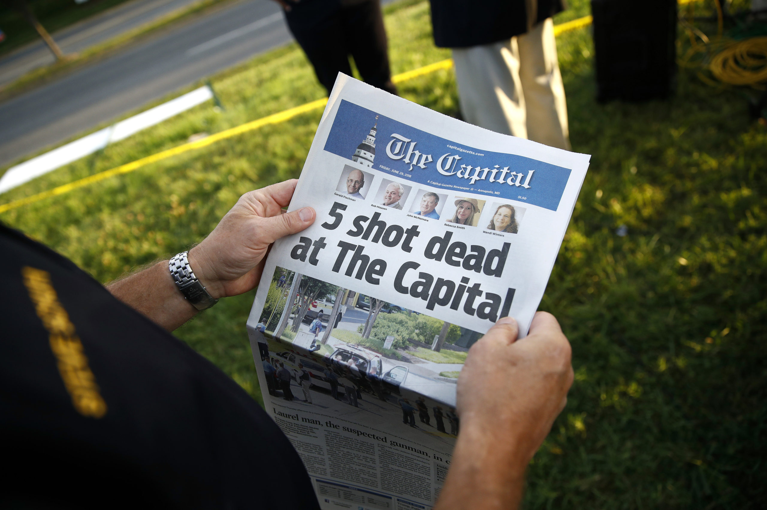 Photo of man reading Capital Gazette one day after a mass shooting at the newspaper
